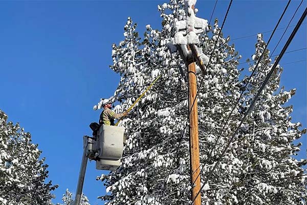 Liberty Tahoe lineworker in bucket truck working on utility lines in winter storm, December 2021